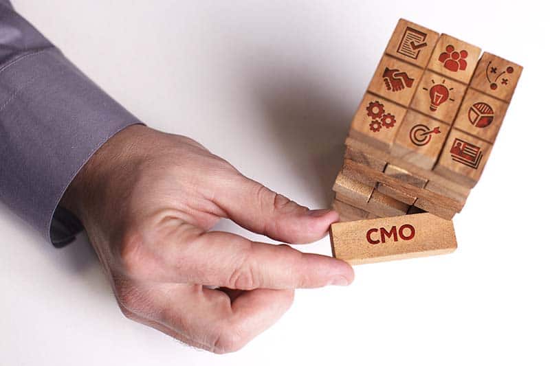 Businessman pulling CMO wood from jenga puzzle
